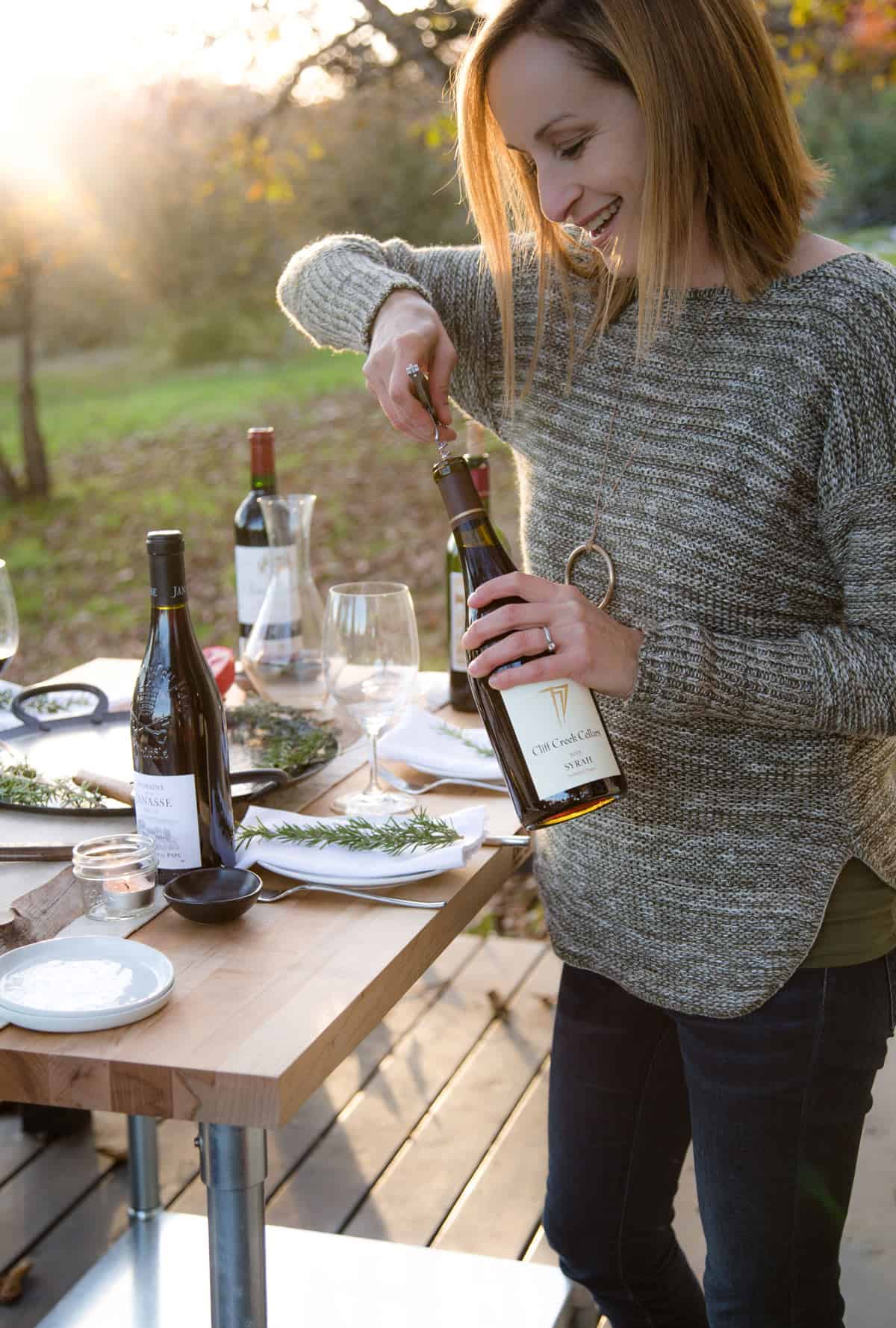 Mary Cressler, sommelier, opening up a bottle of wine for a Thanksgiving dinner spread