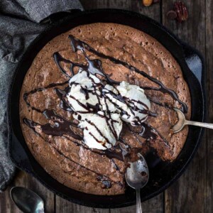 A smoked brownie in a cast iron pan topped with ice cream.