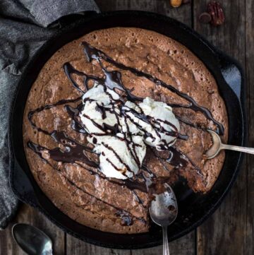 A smoked brownie in a cast iron pan topped with ice cream.