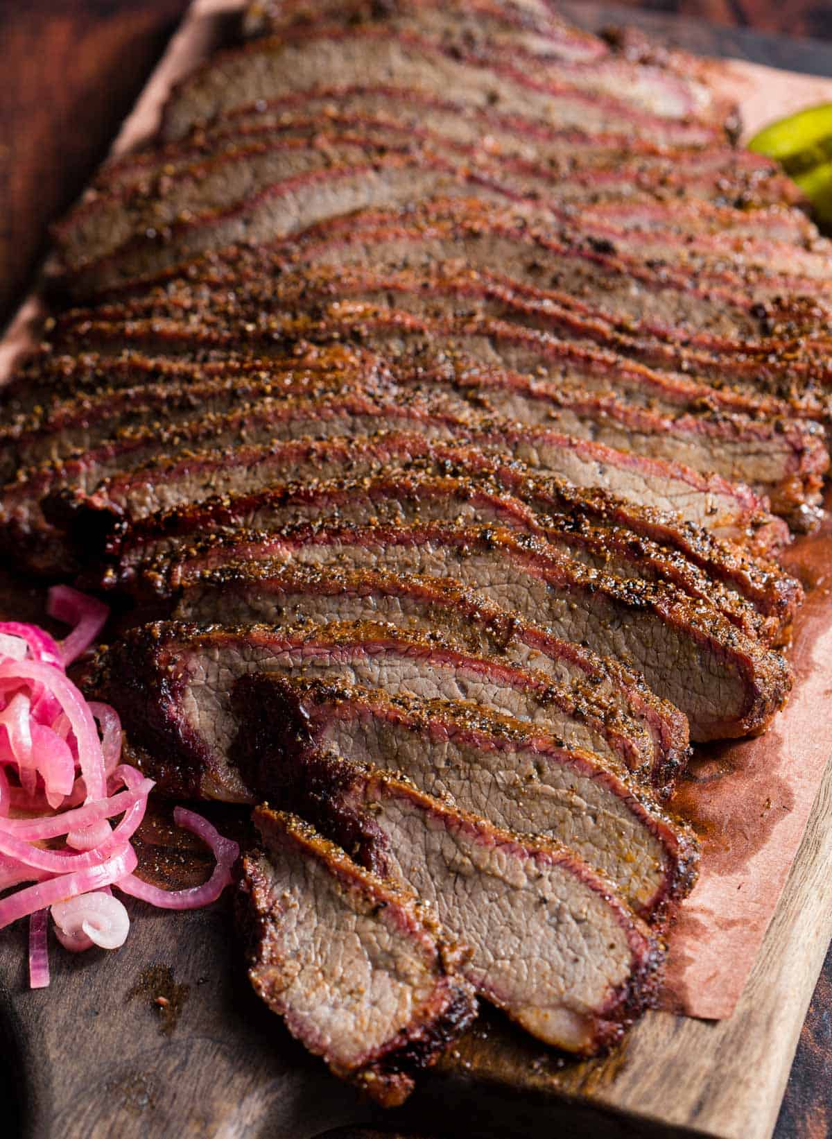 Slices of smoked brisket flat on a platter with garnishes