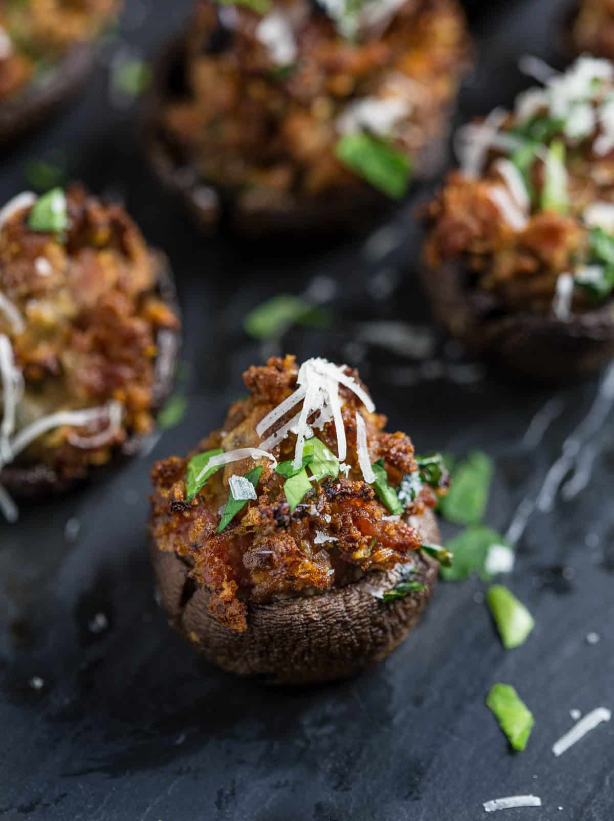 A smoked sausage filled stuffed mushroom appetizer on a black platter