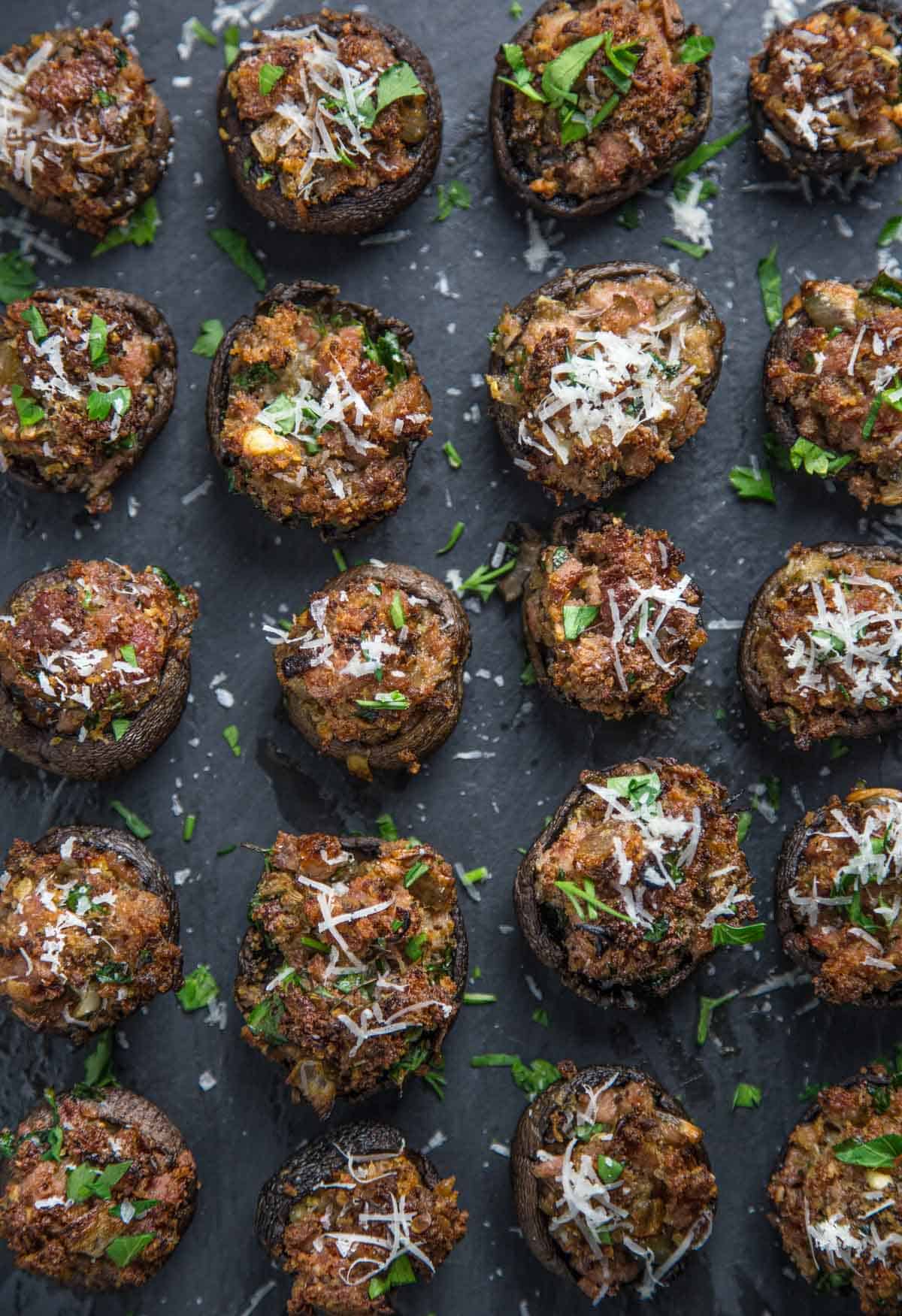 Sausage Stuffed Mushrooms on a platter with shaved parmesan cheese.