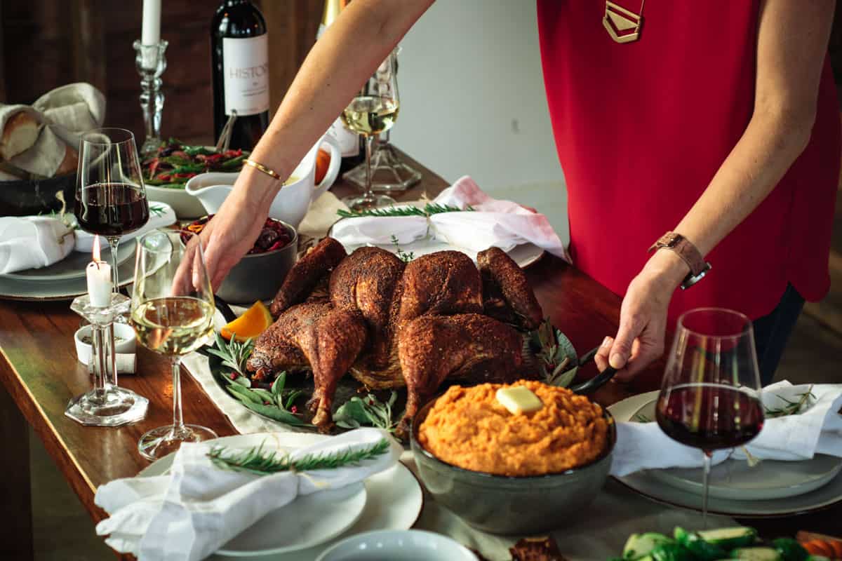 mary cressler placing a smoked spatchcocked turkey on a thanksgiving table