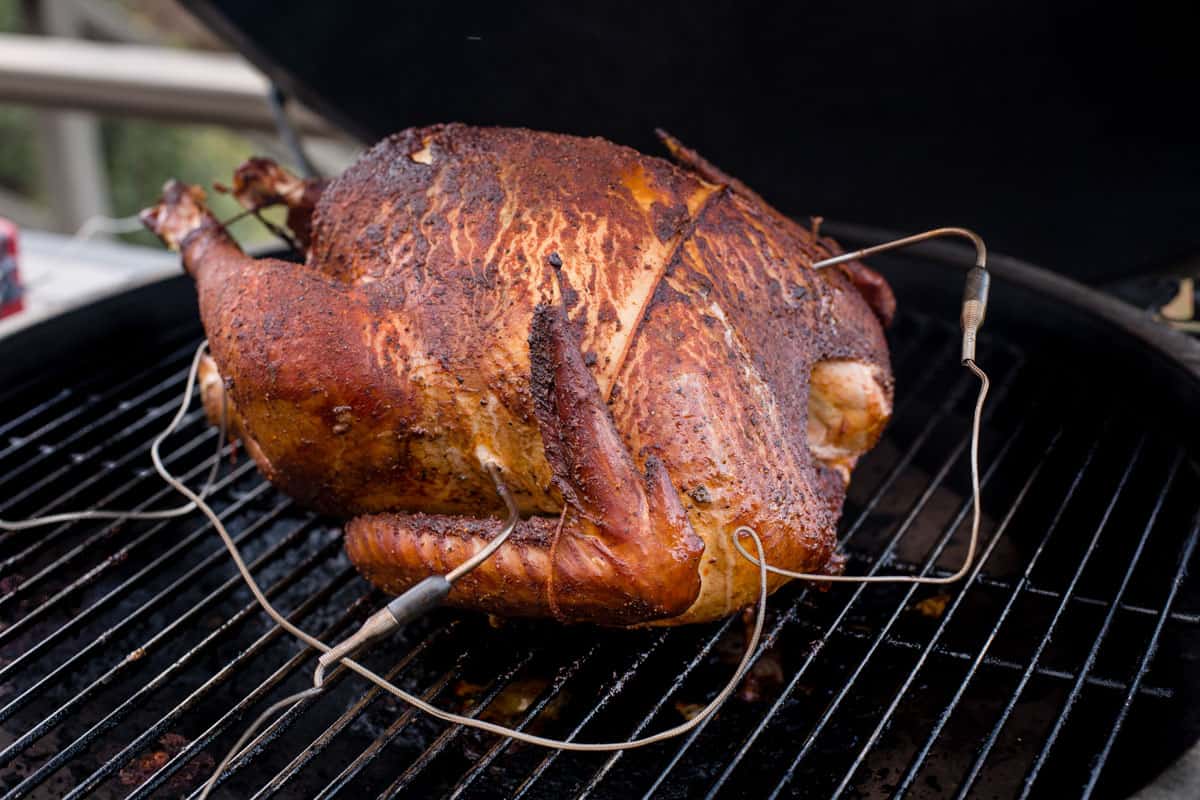 A whole turkey cooking on a smoker