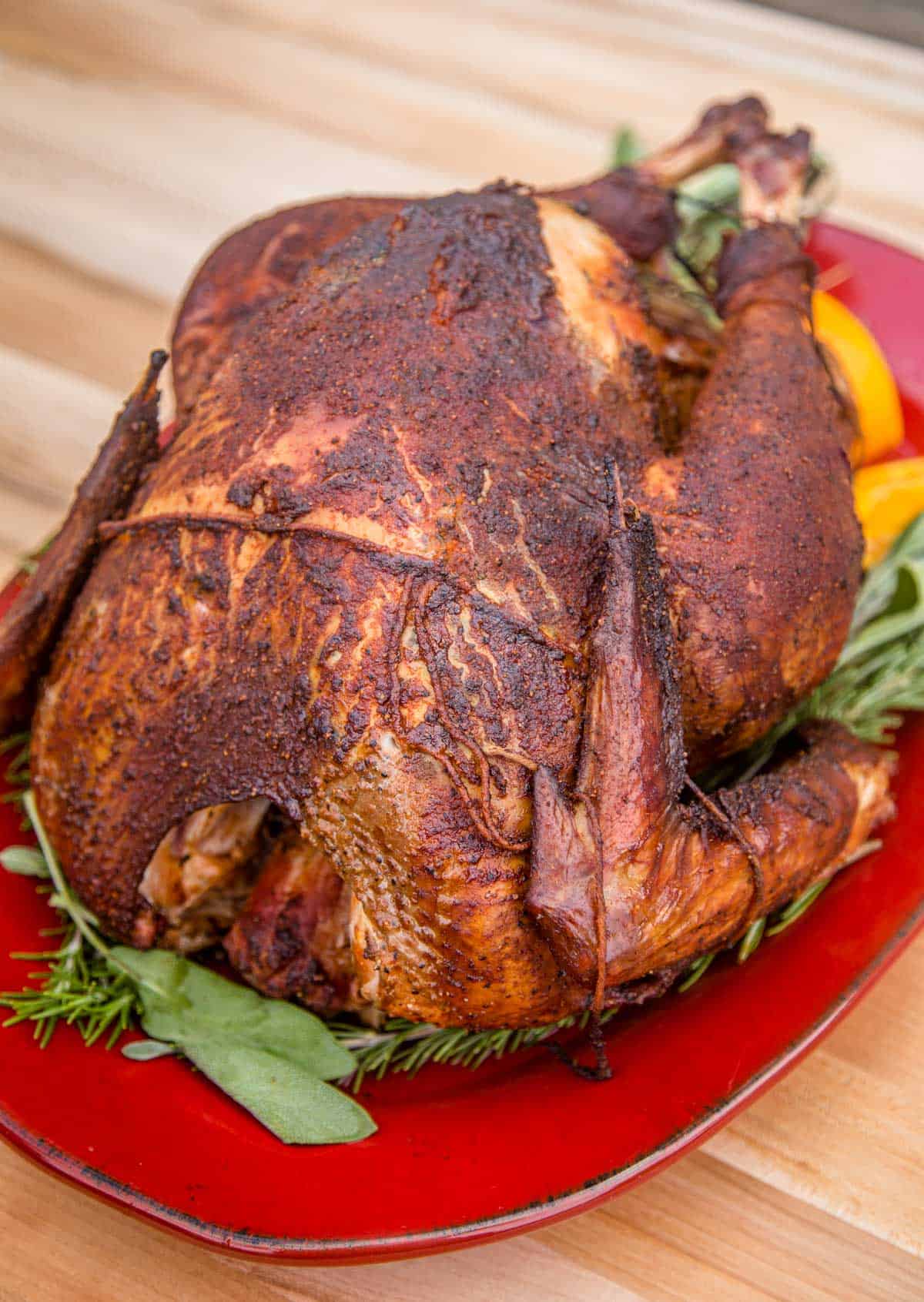 A whole smoked turkey made with a Bourbon brine on a red platter