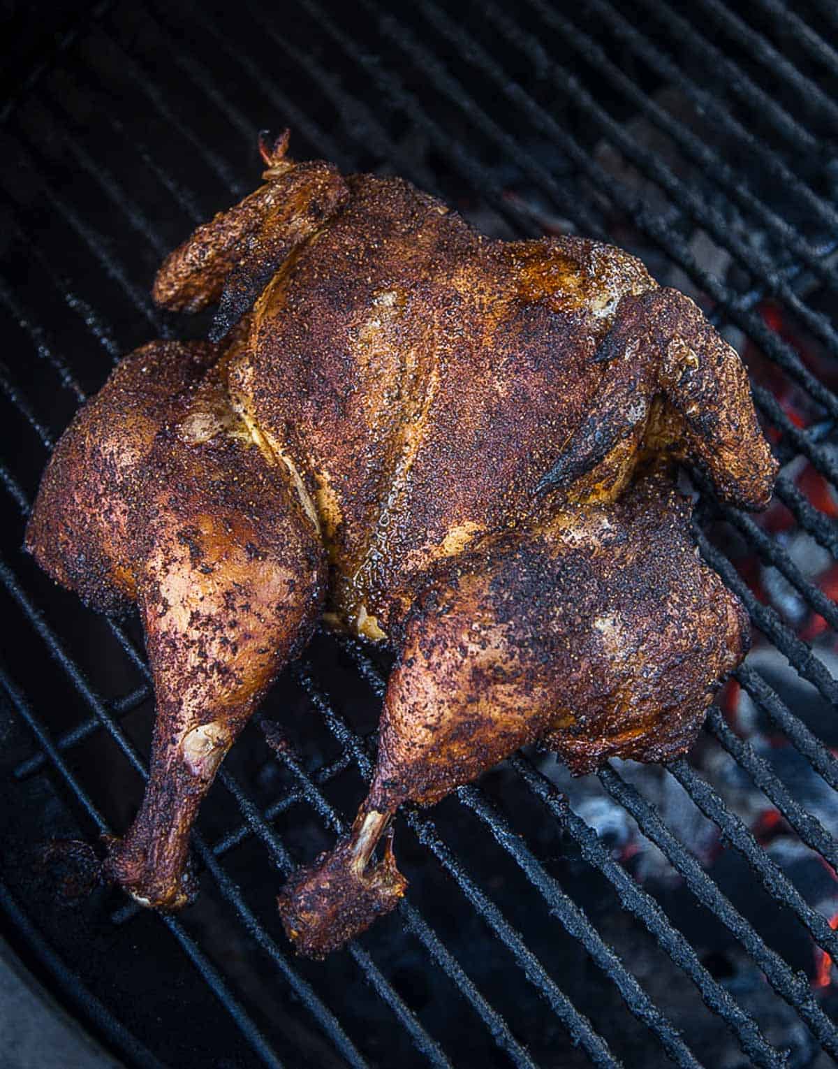 A spatchcocked chicken cooking on a grill