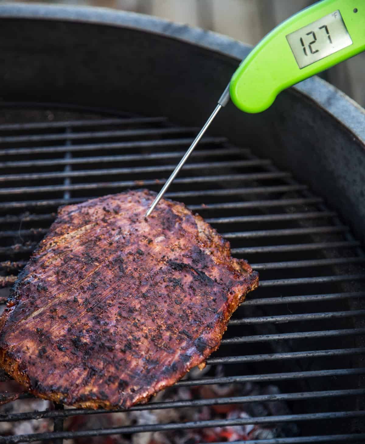 Taking the temperature of a grilled flank steak with a Thermoworks MK4 digital thermometer