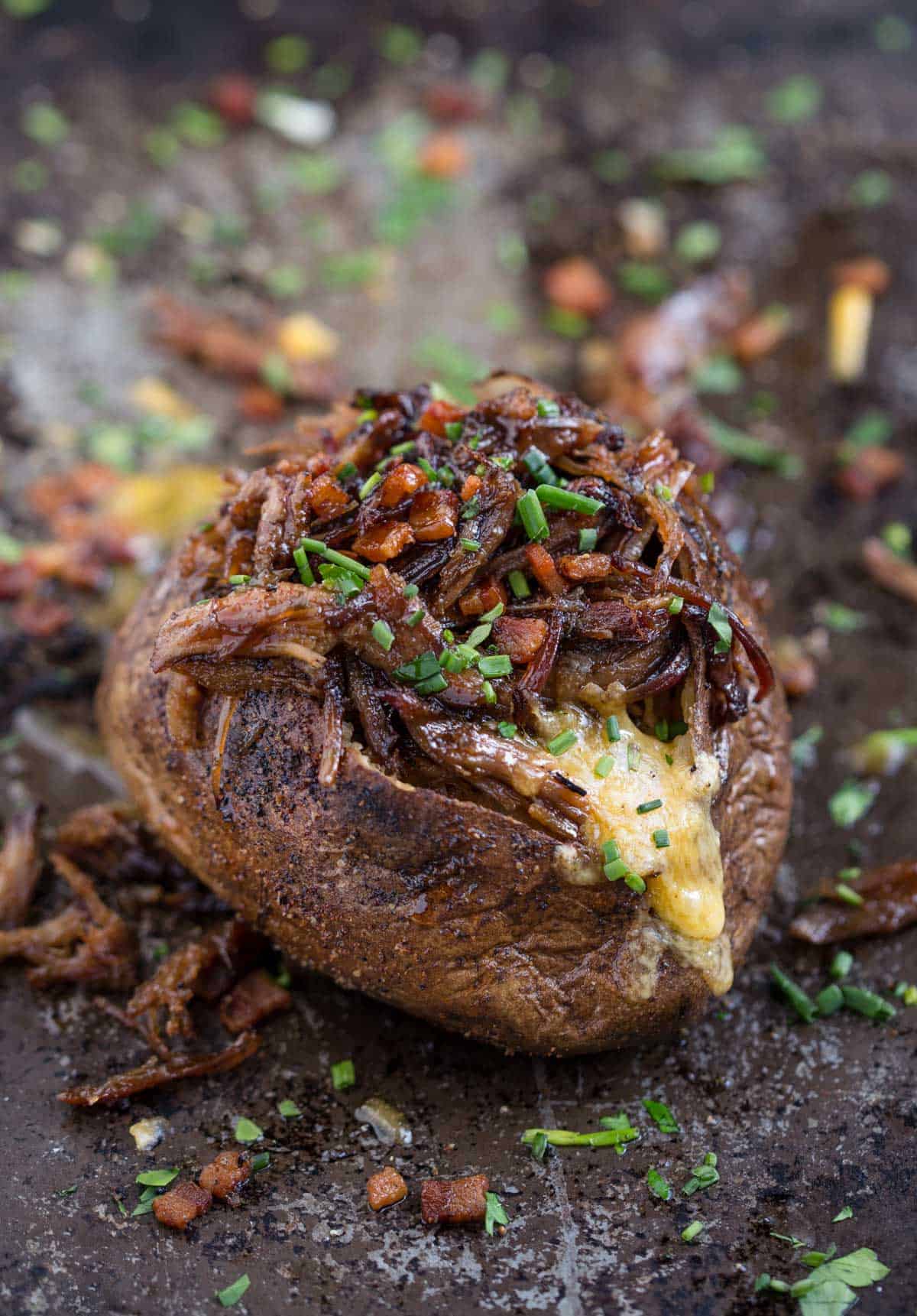 A loaded grilled baked potato topped with bbq pulled pork