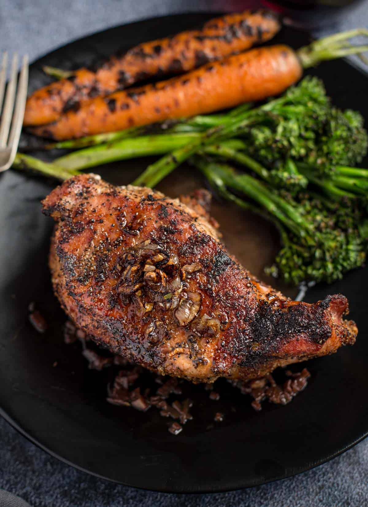 Grilled Pork Chop with a Red Wine Pan Sauce on a platter with some vegetables
