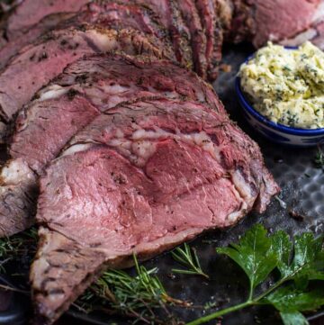 Grilled prime rib slices with compound butter on platter.