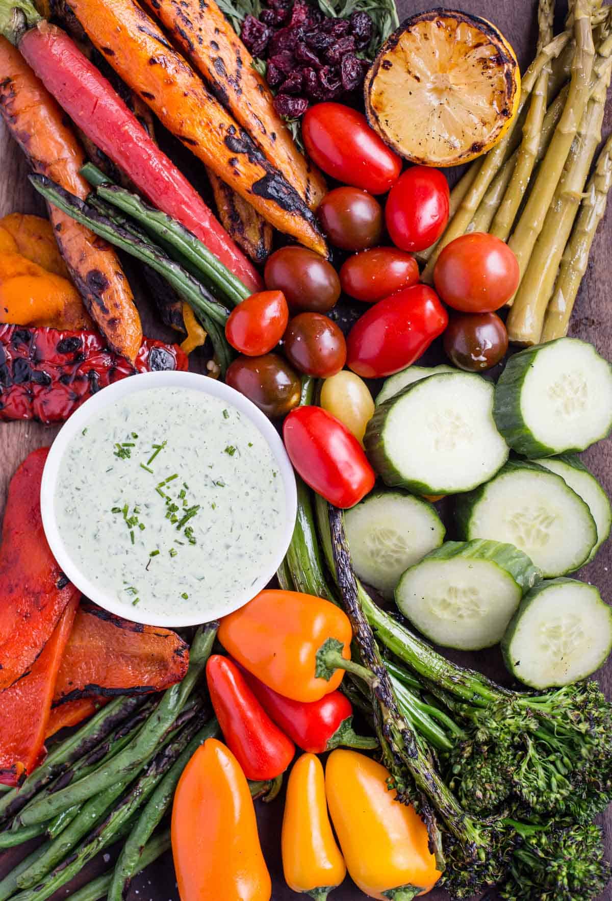Lots of cut up and colorful vegetables on a platter with a green dipping sauce for the ultimate crudités appetizer