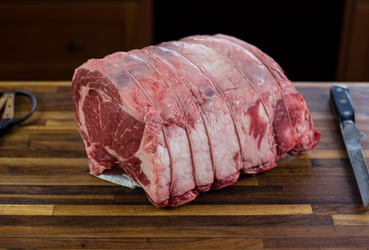 A raw 4-bone prime rib on a cutting board 