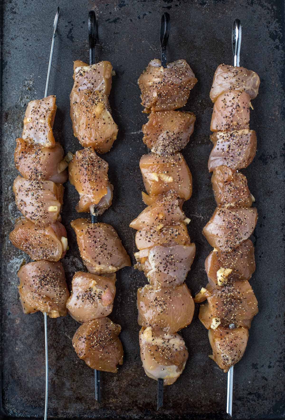 cubed up pieces of marinated chicken on a skewer 