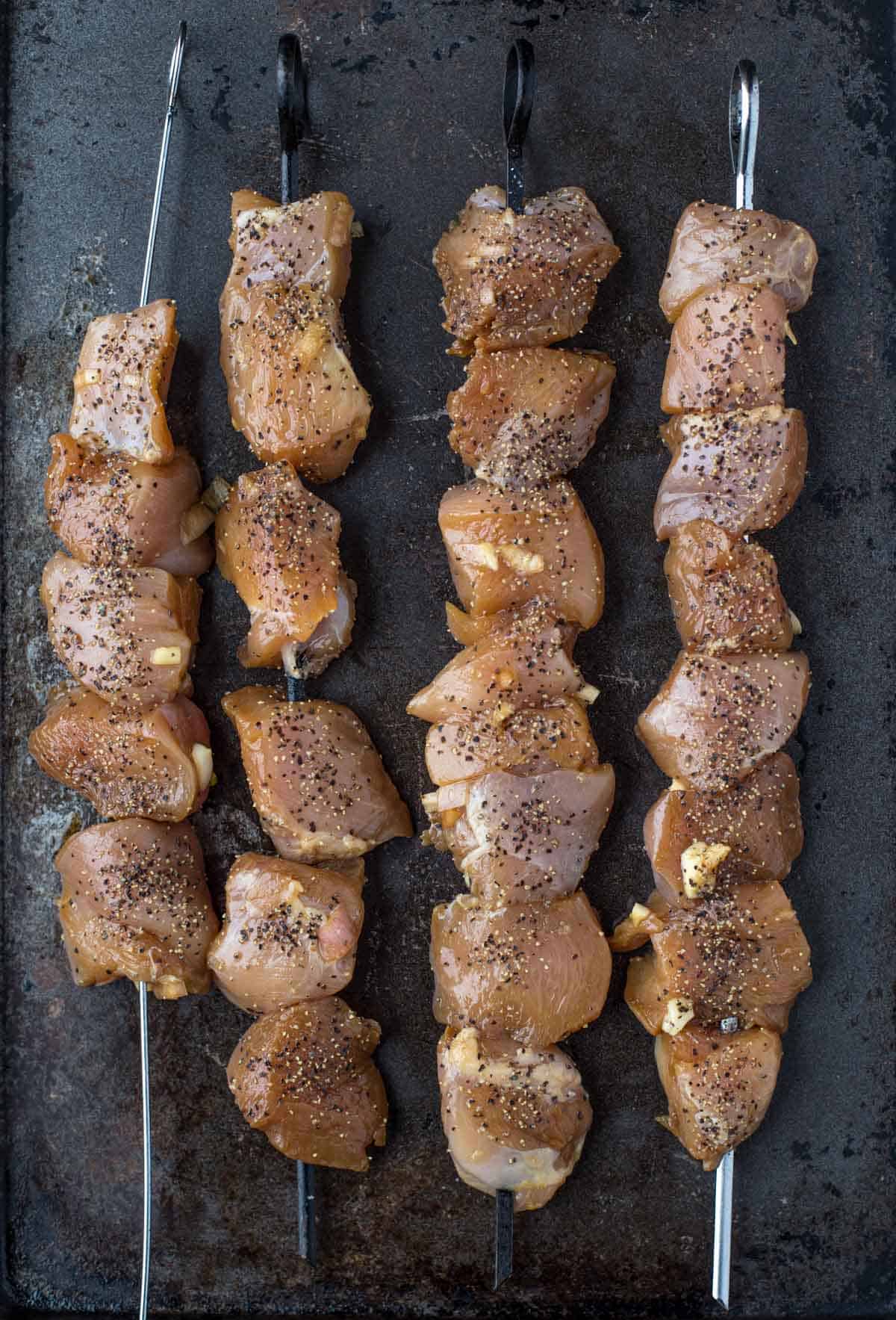 cubed up pieces of marinated chicken on a skewer