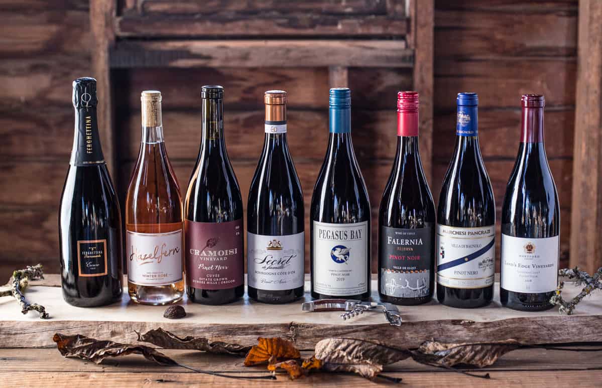 Several bottles of Pinot Noir in different styles on a wood board