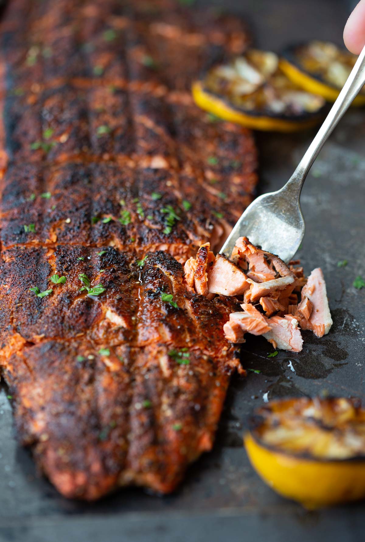 Grilled blackened salmon fillet on a sheetpan with a slice on a fork