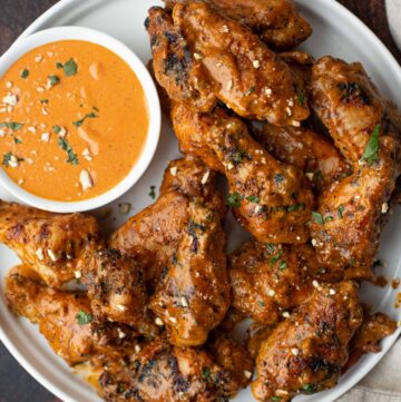 Grilled Chicken Wings with Spicy Peanut Sauce on a platter with dipping sauce
