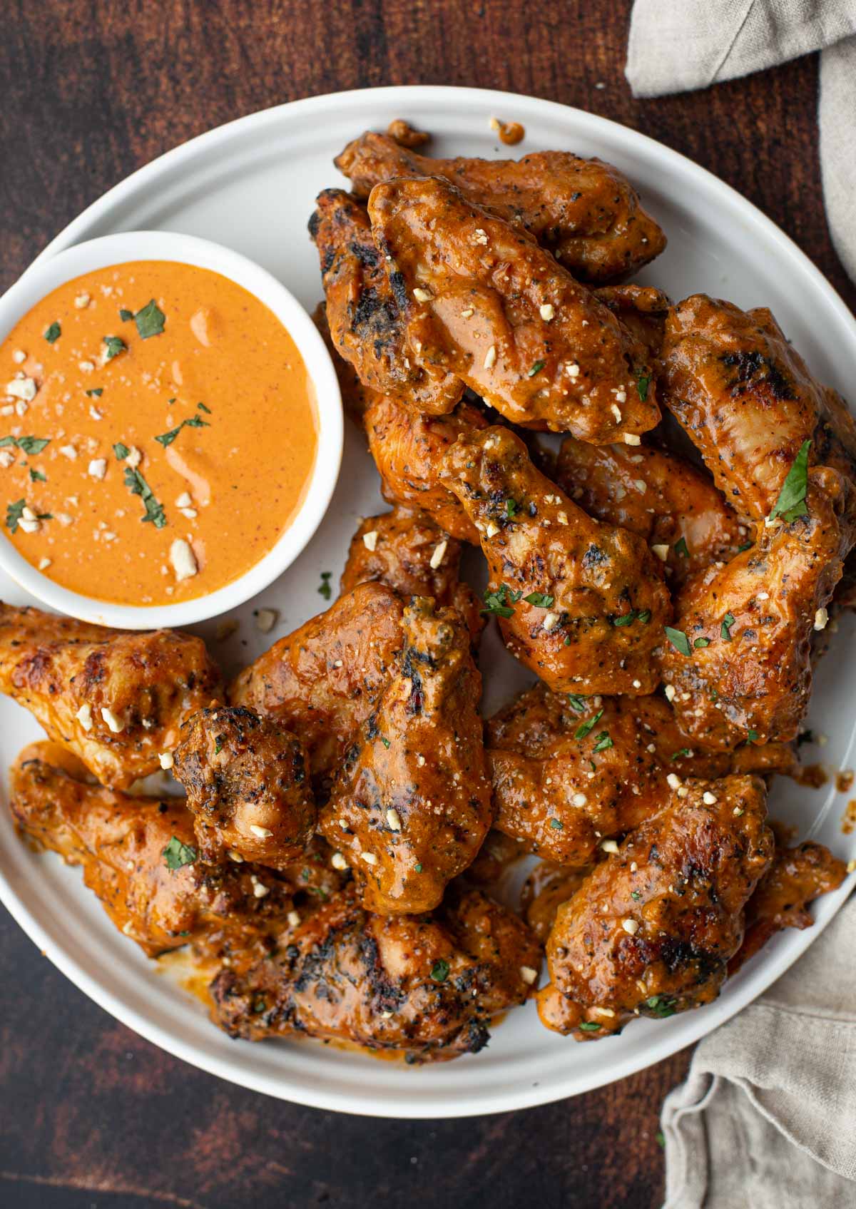Grilled chicken wings on a plate with spicy peanut sauce.