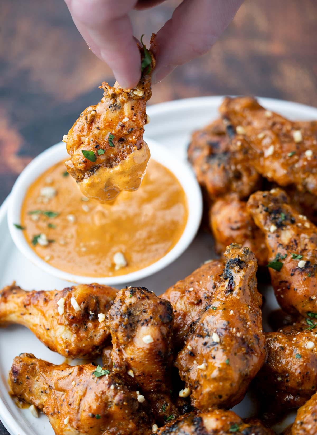 Dipping a Grilled Chicken Wing into a Spicy Peanut dipping sauce