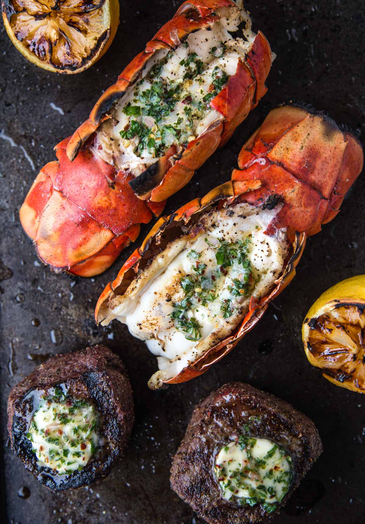 Two Grilled Lobster Tails and two Grilled Filet Mignon resting on a platter