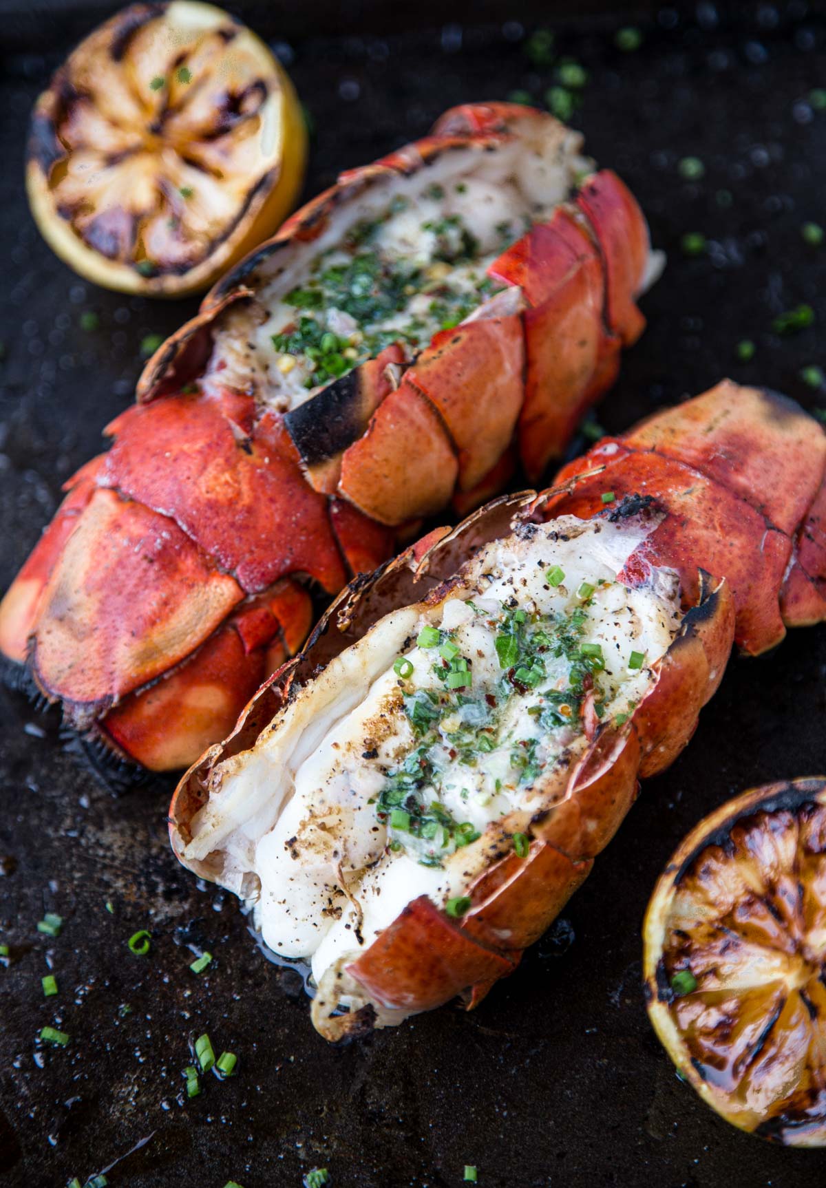 Two Grilled Lobster Tails with an Herb Compound Butter on a serving platter