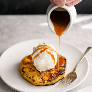 Pouring rum glaze over ice cream and grilled pineapple.