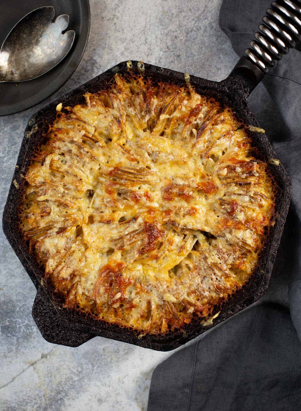 Grilled Hasselback Potato Gratin in a cast iron pan.