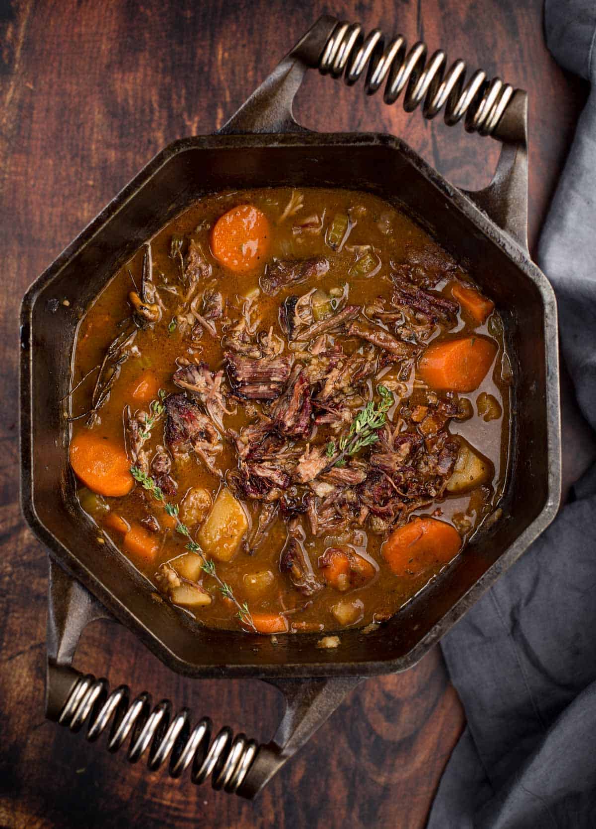 A cast iron pot with smoked short rib Irish stew