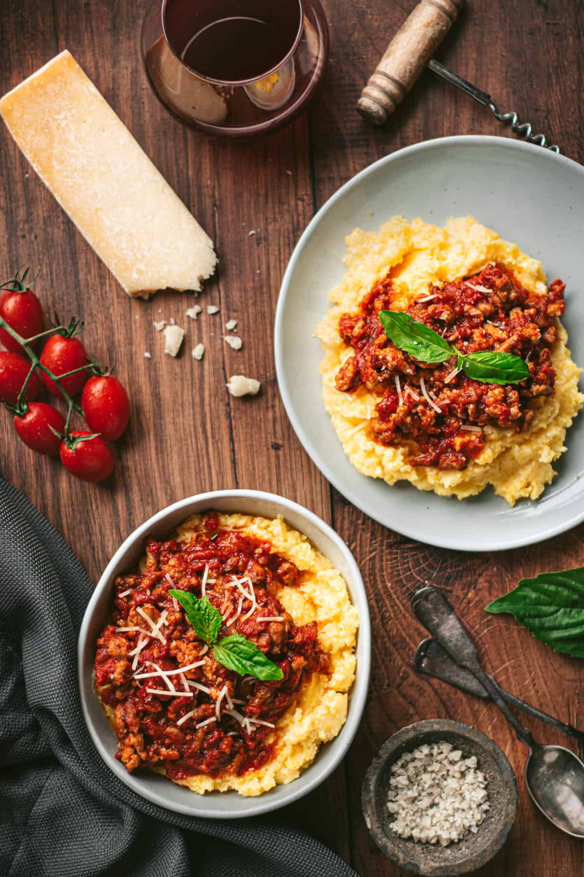 two servings of polenta and smoked sausage ragu on a wooden tabletop