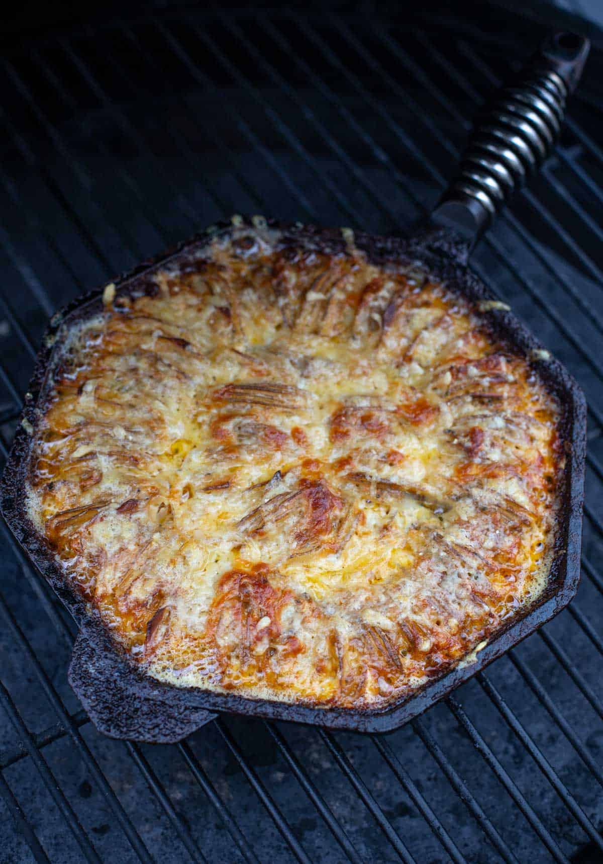 Hasselback Potato Gratin in a cast iron pan on the grill