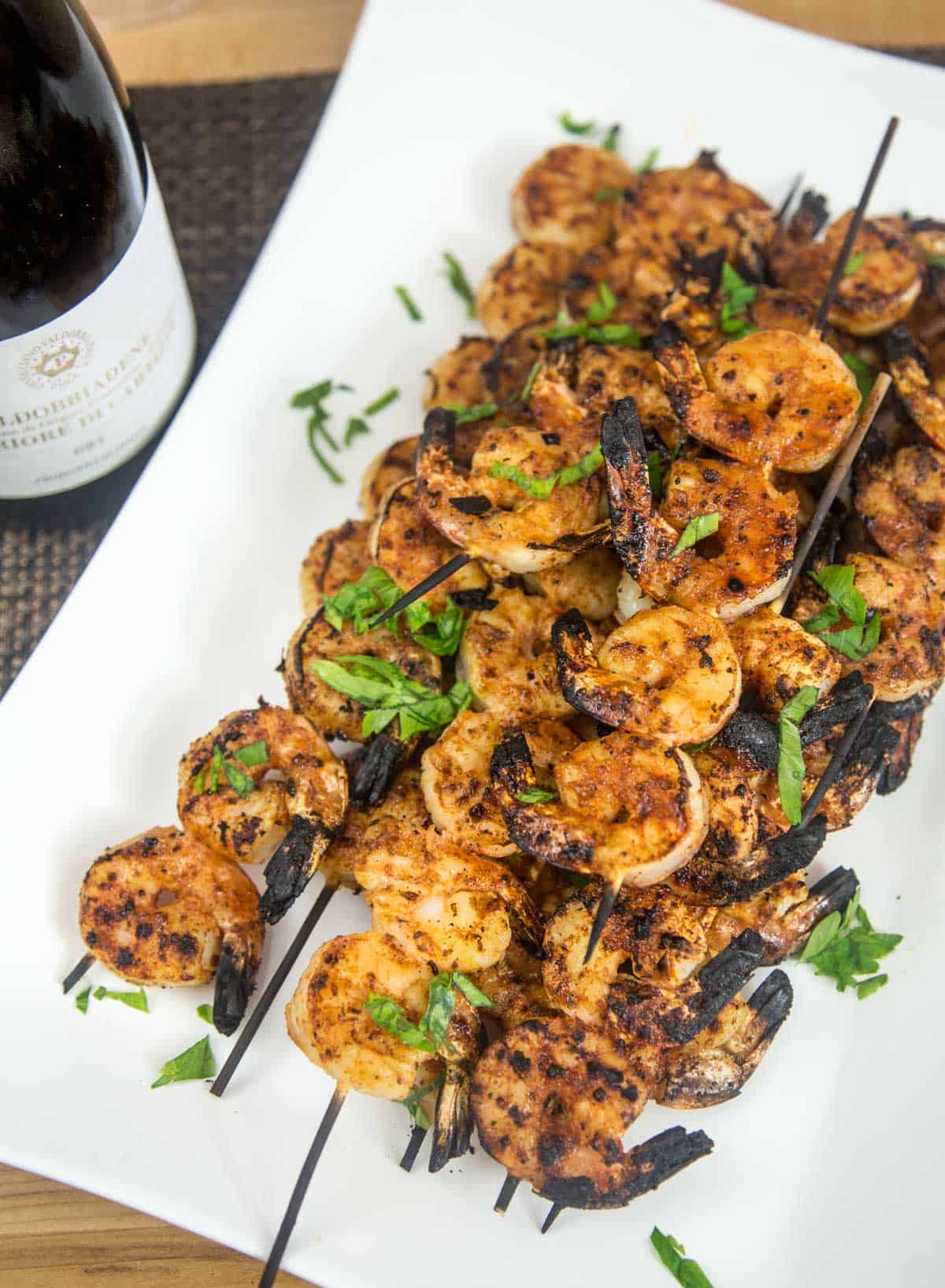 A platter of grilled shrimp skewers wit a bottle of Prosecco wine pairingS