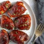 Pellet grilled chicken thighs, glazed, and on a plate.