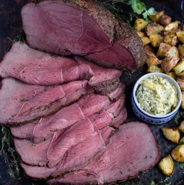 Top Sirloin Smoked Roast Beef on a platter with potatoes.