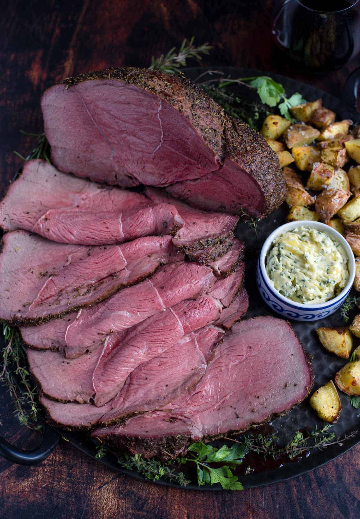 Top Sirloin Smoked Roast Beef on a platter with potatoes.