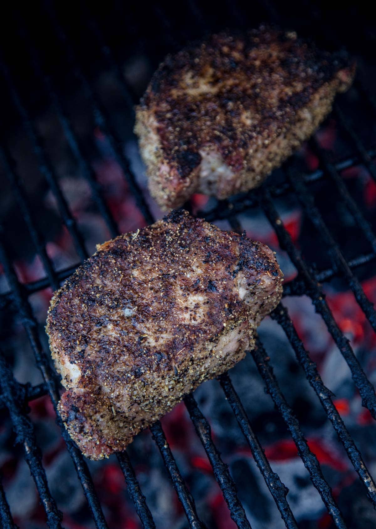 Two thick pork chops cooking over the grill