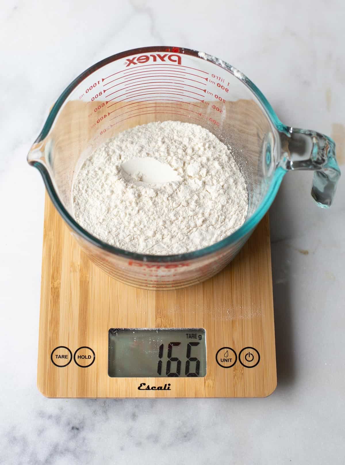 A digital scale measuring flour in a glass dish