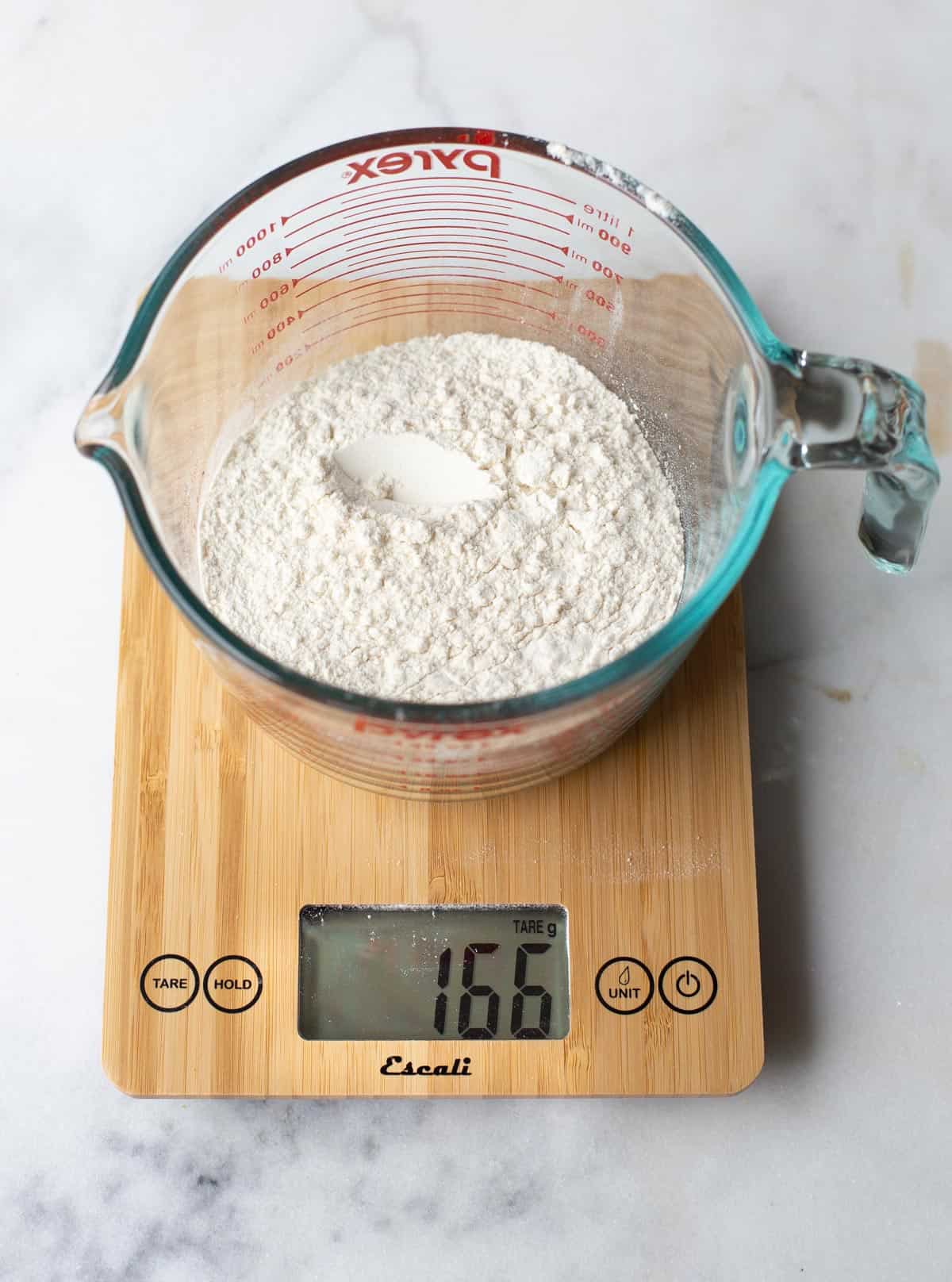 A digital scale measuring flour in a glass dish