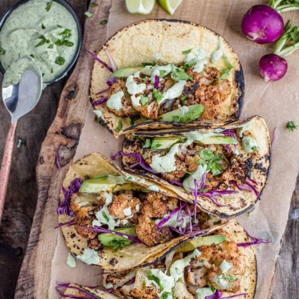 Grilled Cauliflower Tacos on a cutting board with sauce.