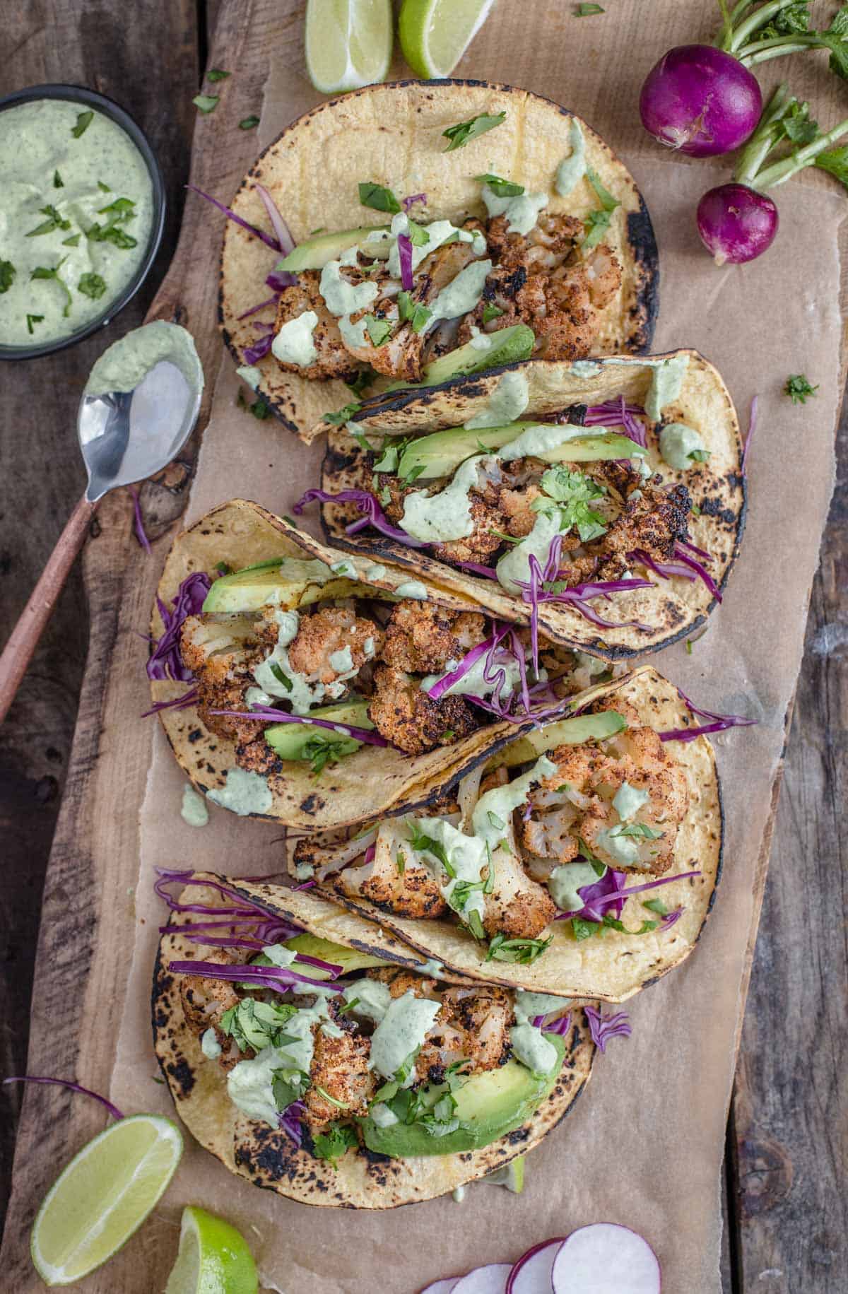 Cauliflower tacos on a wood board topped with taco toppings