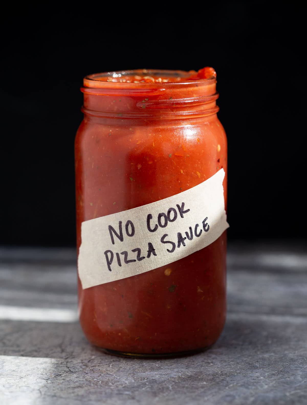 A mason jar filled with homemade No Cook Pizza Sauce.