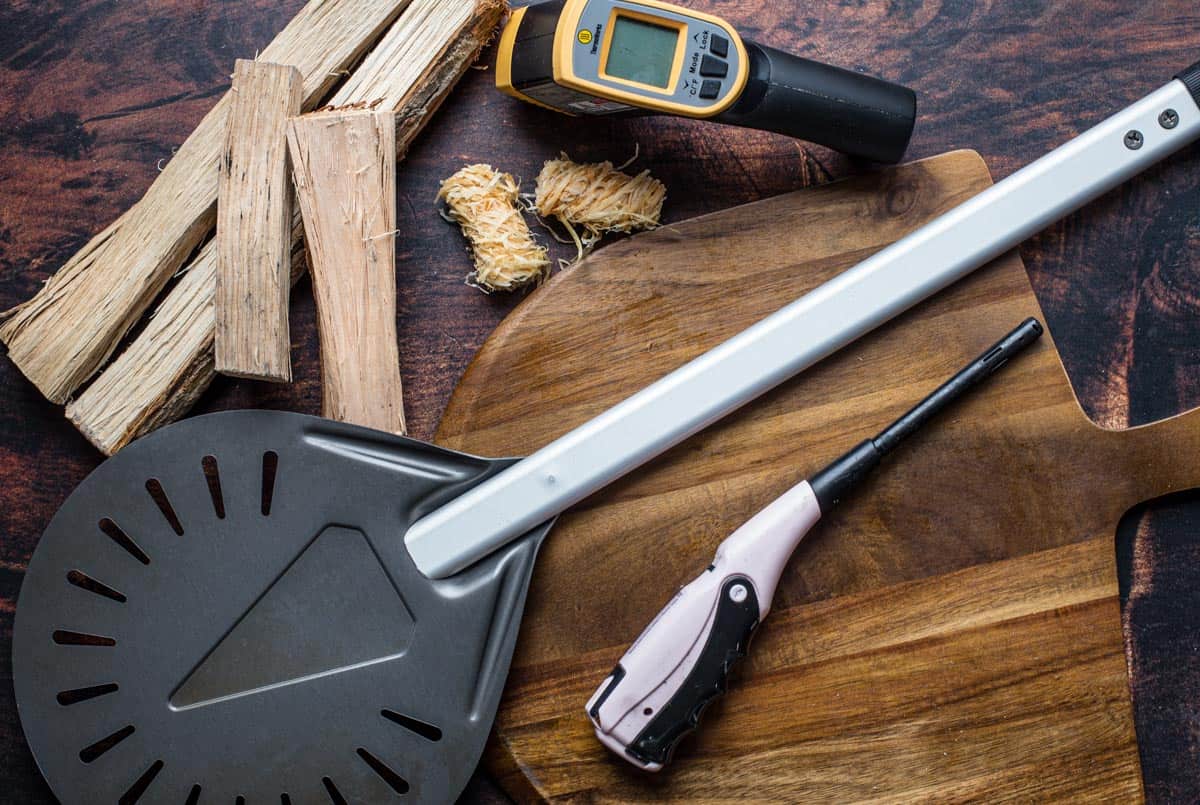 Essential tools for making wood fired pizzas on a Gozney Dome, on a wood board