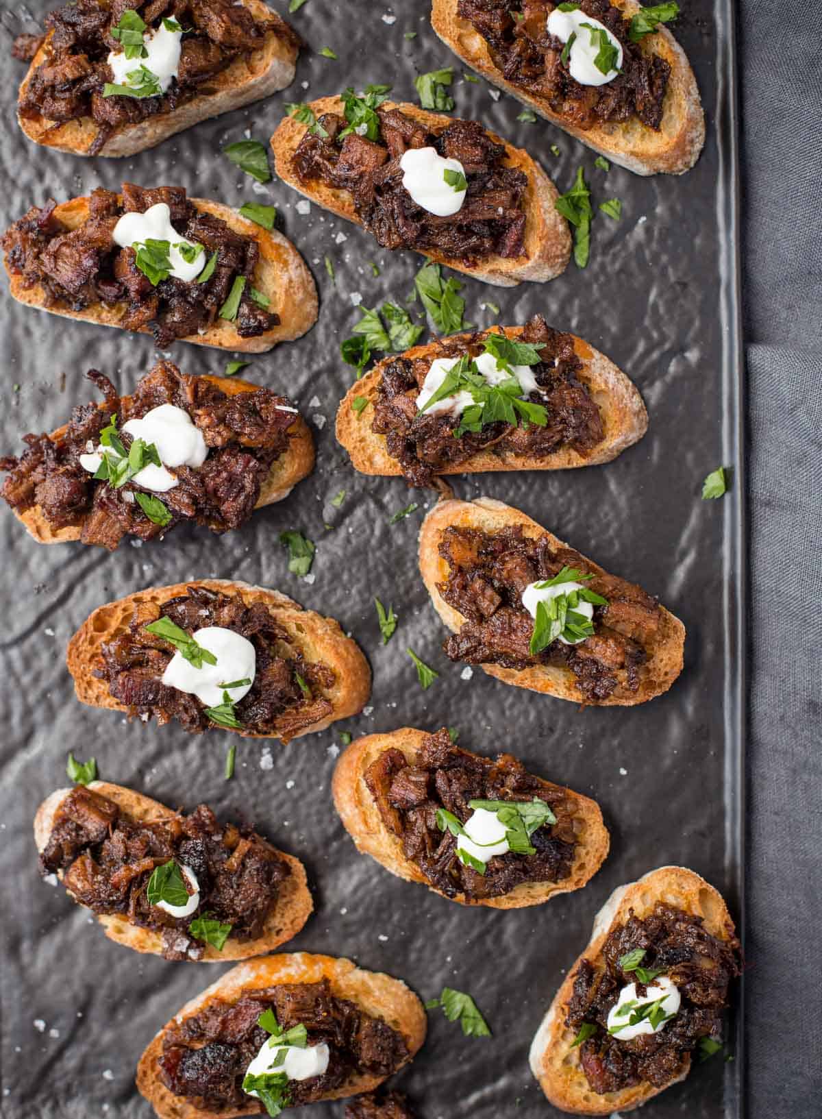 Brisket bruschetta crostini on a serving platter.