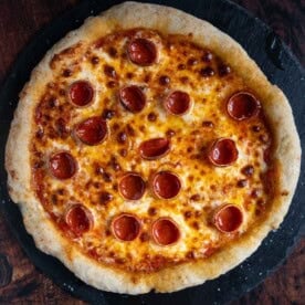 Gluten Free Pizza Dough topped with cheese and pepperoni for a GF pepperoni pizza.