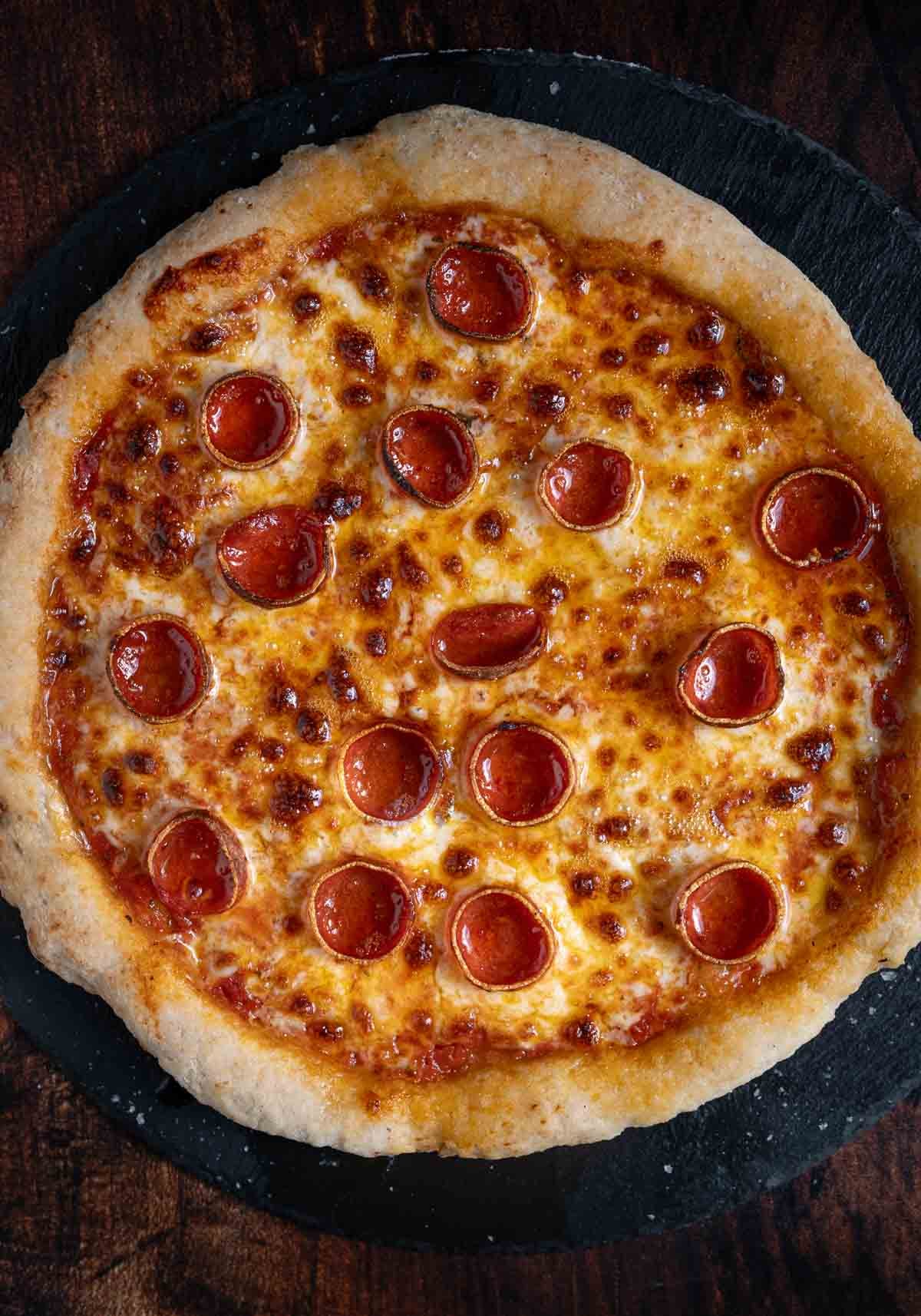 A pepperoni pizza made on the best Gluten-Free Pizza Dough on a black serving tray.