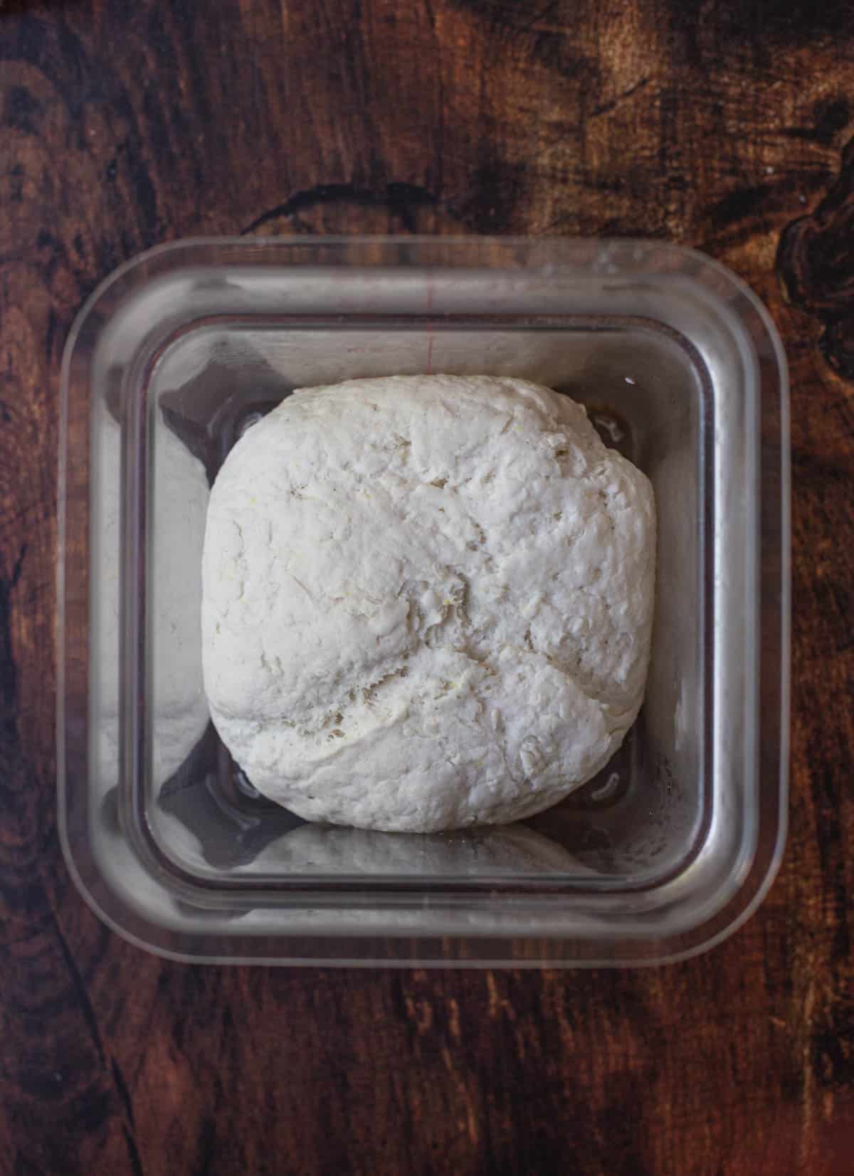 Top down view of gluten free flour in a container going through the first rise.