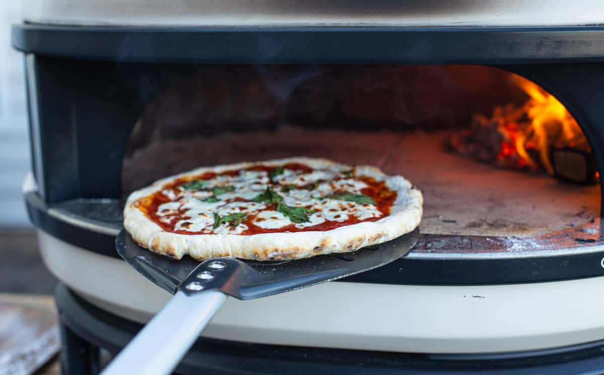 Using a pizza turning peel on an outdoor pizza oven.