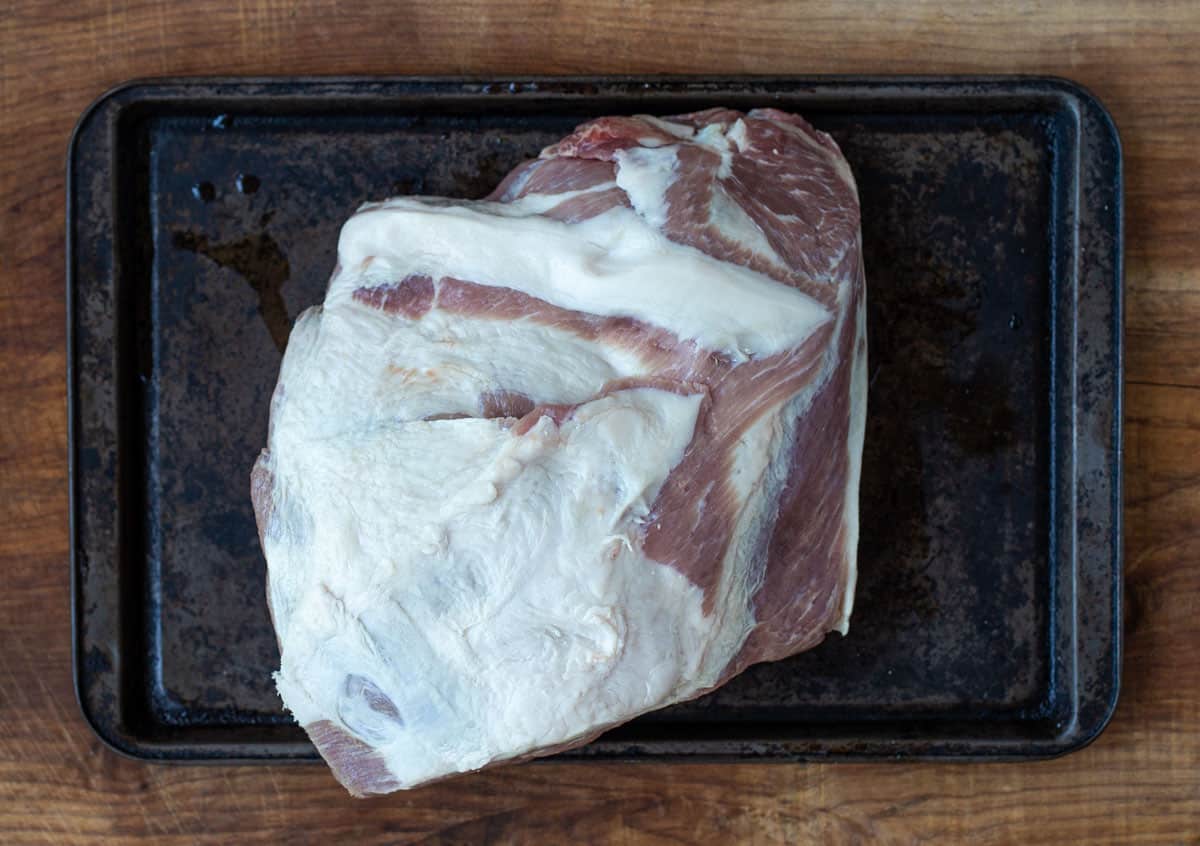 A raw pork shoulder on a baking sheet