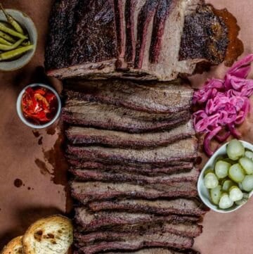 Smoked brisket sliced on butcher paper with pickled vegetables.