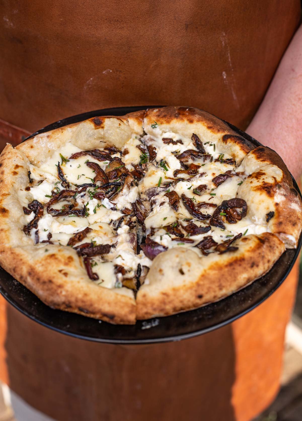 Holding the white sauce pizza on a pizza peel.