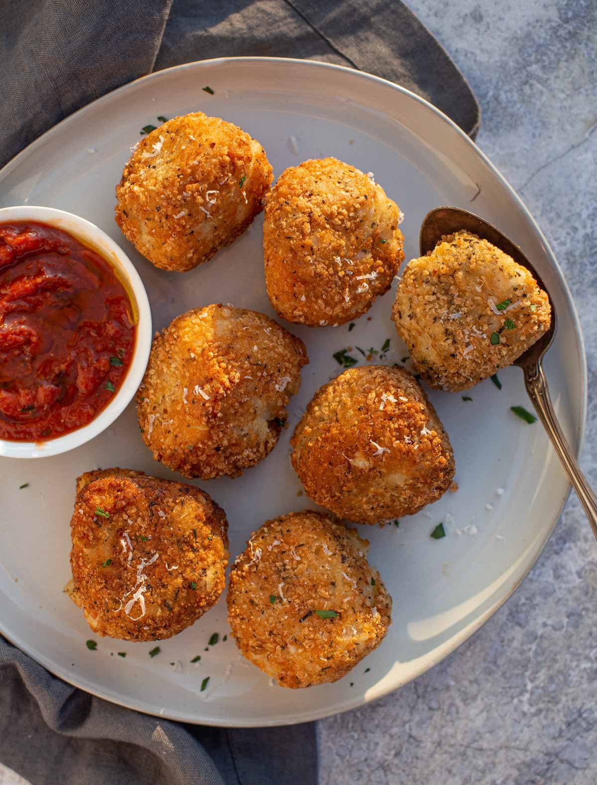 Arancini (Sicilian rice balls) on a platter with a dipping sauce